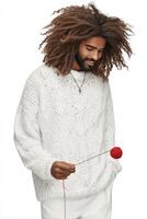 Smiling Man with Curly Hair Holding Red Pom Pom in White Sweater photo