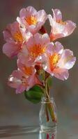 Beautiful pink flowers in a clear vase with green leaves displayed on a shiny surface photo