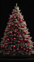 Christmas tree decorated with red ornaments and lights glowing in a dark setting photo