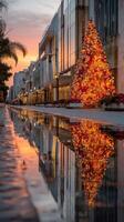 Brightly illuminated Christmas tree reflects in calm water at a city street during sunset in a festive holiday atmosphere photo