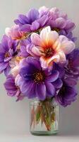 Vibrant bouquet of blooming purple and pink flowers in a glass jar displayed indoors during daylight photo