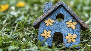 A small wooden house with flowers painted on it is sitting in the grass photo