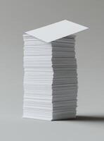 Towering stack of white papers, a blank business card atop photo