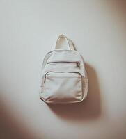 Minimalist off-white backpack, simple and stylish design, hangs against a light beige background photo