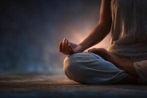 A person sits in a meditative pose with crossed legs, hands in a mudra, and a calm expression. Soft light accentuates the tranquil atmosphere, promoting inner peace and mindfulness. photo