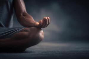 A person sits cross-legged in a calm atmosphere, practicing meditation. The focus is on the hands in a mudra, with soft lighting enhancing the tranquil mood. photo