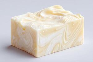 A beautifully crafted rectangular block of handmade soap features creamy white and beige swirls. The smooth texture hints at its moisturizing properties, making it suitable for personal care. photo