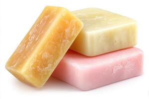 Three bars of natural handmade soaps in yellow, pink, and cream are displayed on a clean white background. Each bar showcases a unique texture, ideal for skincare and personal care routines. photo