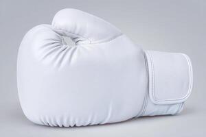 A white boxing glove is positioned to highlight its round shape and padded surface. The glove displays clean lines and a smooth texture, emphasizing its professional quality and craftsmanship. photo