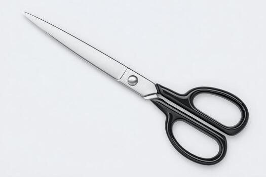 A pair of scissors featuring a shiny metal blade and comfortable black handles is placed on a clean white background, emphasizing their sharpness and utility for various cutting tasks. photo