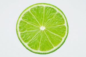 A circular slice of lime presents its vivid green interior, highlighting the juicy segments and fresh appearance. The bright color adds a refreshing touch against a plain white background. photo