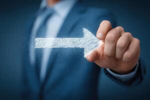 A business professional in formal attire points an illuminated arrow forward, symbolizing direction and focus. photo