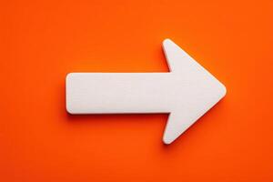 A white arrow pointing right is placed on a bright orange surface. This design is ideal for signage or directional guidance. The contrast creates an eye-catching visual appeal. photo