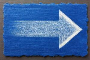 A vibrant blue rectangular surface features a large, white arrow on the right side, suggesting direction. The arrow appears drawn with a fine texture, enhancing visibility and clarity. photo