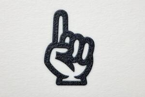 A black hand symbol with an extended index finger is displayed on a clean white surface. This gesture signifies number one and can represent encouragement or branding. photo