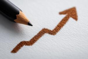A black pencil rests beside a brown graph that depicts an upward trend. The drawing suggests progress and success. The focus is on the sharp pencil tip, highlighting creativity and strategy. photo