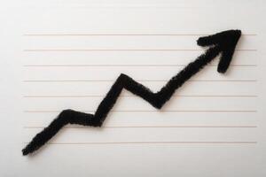A black chalk line illustrating a zigzagging growth trend is drawn on a sheet of lined paper. The line emerges from the bottom left, rising toward the upper right, signifying upward progress. photo