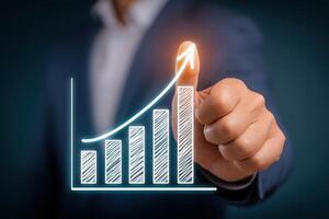 A hand points to a rising graph, symbolizing growth and success in business. The background is dark, emphasizing the upward trend depicted. This moment captures optimism and progress. photo