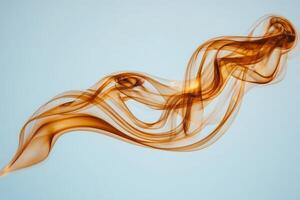 Delicate strands of amber smoke flow gracefully through the air, forming elegant shapes and patterns against a soft blue background, showcasing the beauty of movement and color. photo