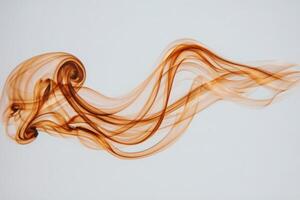 Swirling brown smoke elegantly dances across a soft light backdrop, forming intricate patterns. The ethereal movement captures a sense of tranquility and artistic beauty. photo