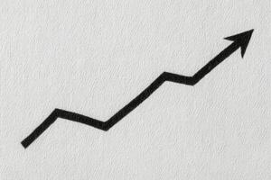 A black zigzag arrow pointing upward is depicted against a light gray textured background. The arrow symbolizes growth and progress, emphasizing a positive trend or increase. photo