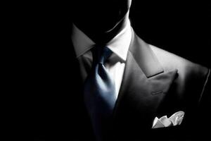 Formal attire showcases a finely tailored suit with a crisp white pocket square and a light blue tie. The dark background emphasizes the elegance and sophistication of the clothing. photo