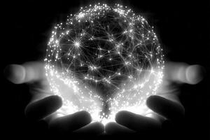 Two hands gently cradle a luminous globe made of interconnected lines and dots, symbolizing global networks and technology. The dark background emphasizes the glow of the globe, creating a contrast. photo