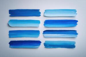 A creative arrangement of blue paint strokes on a light surface showcases different shades, blending from deep navy to soft azure. This artistic display highlights color variation and texture. photo