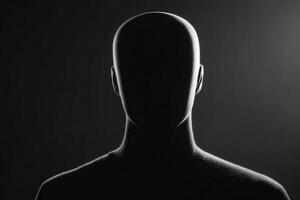 A faceless figure is centered in darkness, illuminated from behind, creating a striking silhouette. The absence of features evokes a sense of mystery and intrigue. photo