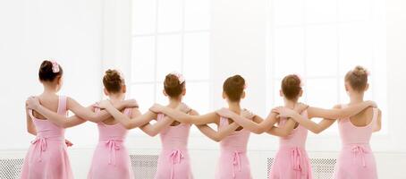 Young girls dancing ballet in studio. Choreographed dance by a group of graceful pretty young ballerinas practicing during class before performance. Classical dance school photo