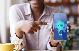 VPN App. Black Woman Pointing At Smartphone With Opened Virtual Private Network Application On Screen, African American Lady Enjoying Modern Technologies For Syber Security, Creative Collage, Closeup photo