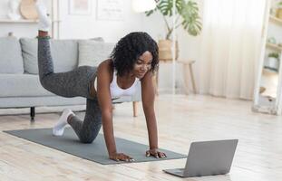 African american girl exercising with online tutorial on laptop at home, empty space photo
