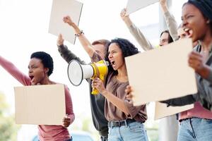 Multiracial group of motivated demonstrators with blank placards and megaphone protesting on the street. International group of people fighting for human rights, showing empty boards, side view photo
