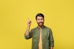 Positive man experiencing AHA moment, having creative idea or pointing finger up at copy space over yellow studio background. Middle aged man gesturing eureka photo