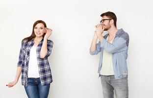Communication and fun. Young casual couple talking through tin can phone, isolated on white background photo