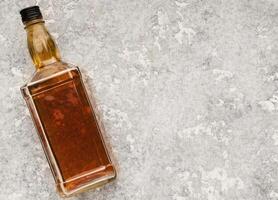 Elite alcohol bottle on gray stone background. Mockup for whiskey, brandy or cognac advertisement, top view, copy space photo