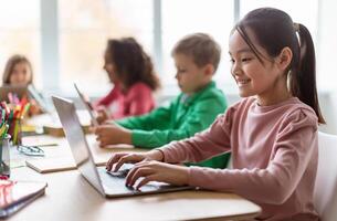 Online Learning. Diverse Children Using Laptop In Modern Classroom At School, Selective Focus On Happy Asian Schoolgirl Browsing Internet On Computer. E-Learning, Education And Technology photo