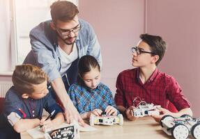 Stem education. Kids creating robots with teacher. Early development, diy, innovation, modern technology concept photo