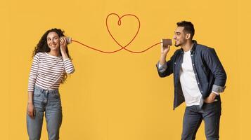 Message With Love. Happy Young Arab Man Telling Romantic Words To His Girlfriend Through Tin Phone With Drawn Red Heart As String, Loving Middle Eastern Couple Posing Over Yellow Background photo