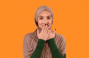 Muslim Lady In Hijab Covering Mouth With Hands Posing Smiling To Camera Standing Over Yellow Studio Background. Rumors Spreading, Oops, Slip Of A Tongue And I Didn't Say It Concept photo
