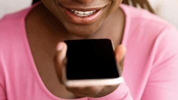 Voice Search Concept. Closeup portrait of black woman using personal assistant app on smartphone at home or recording audio message, enjoying modern technologies and gadgets, selective focus photo