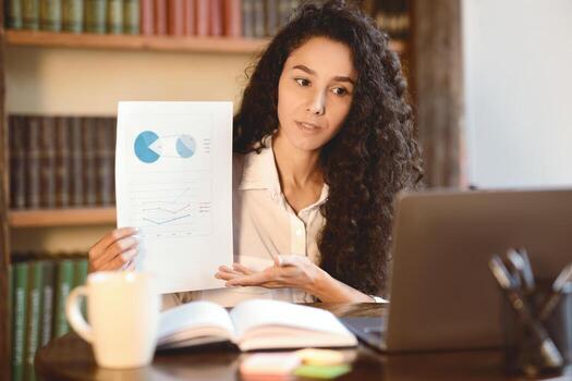 teletrabajo enfocado hembra gerente teniendo videollamada en computadora portátil, dando virtual presentación. mujer demostración documento papel con cuadro, grafico y diagrama a cámara web y hablando, explicando reporte foto