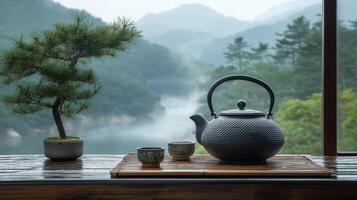 A beautiful tea set is arranged by a window with a misty mountain view during early morning. photo