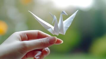 A person holding a paper crane in their hand photo