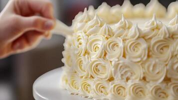 Close-up view of a hand decorating a frosted cake with buttercream roses. photo