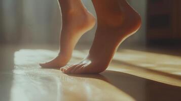 Barefoot feet stepping on a light-filled wooden floor. photo