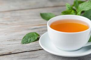 Aromatic Mint Tea in a White Cup on Wooden Table photo