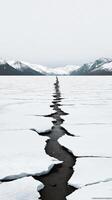 Majestic Winter Landscape A Serene Frozen Lake with a Crack in the Ice, Surrounded by Snow Covered Mountains. A Breathtaking View of Nature's Beauty photo