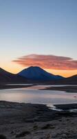Sunset over Volcanic Lake in Andes Mountains, Chile. Breathtaking landscape panorama, serene and majestic nature scenery at dawn. Peaceful reflection of vibrant colors in the still water. photo