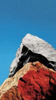 Majestic Rock Formation A Stunning Landscape of Color and Texture. The interplay of grey, red, and black rocks against a vibrant blue sky creates a breathtaking natural masterpiece. photo